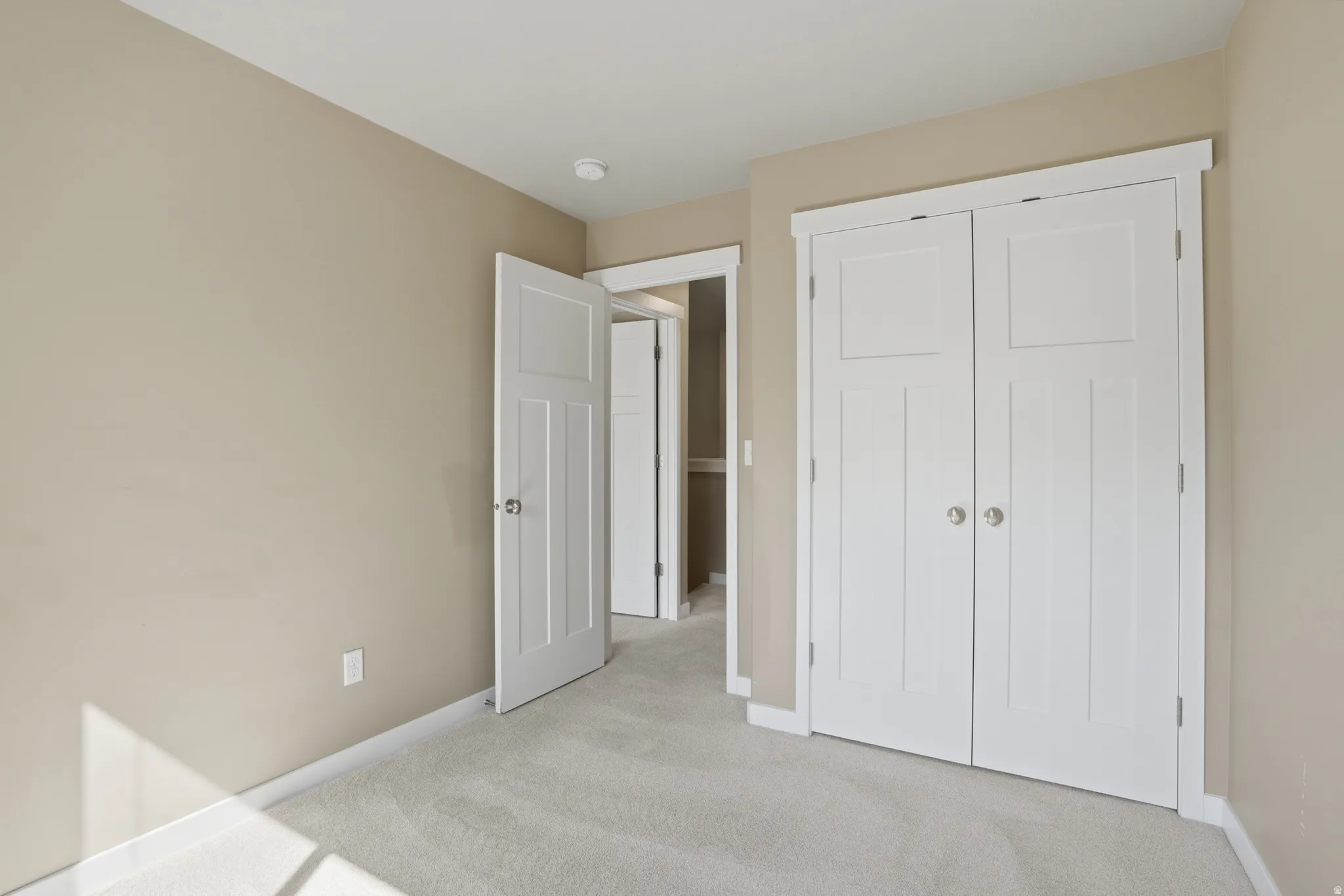 Unfurnished bedroom featuring light carpet and a closet