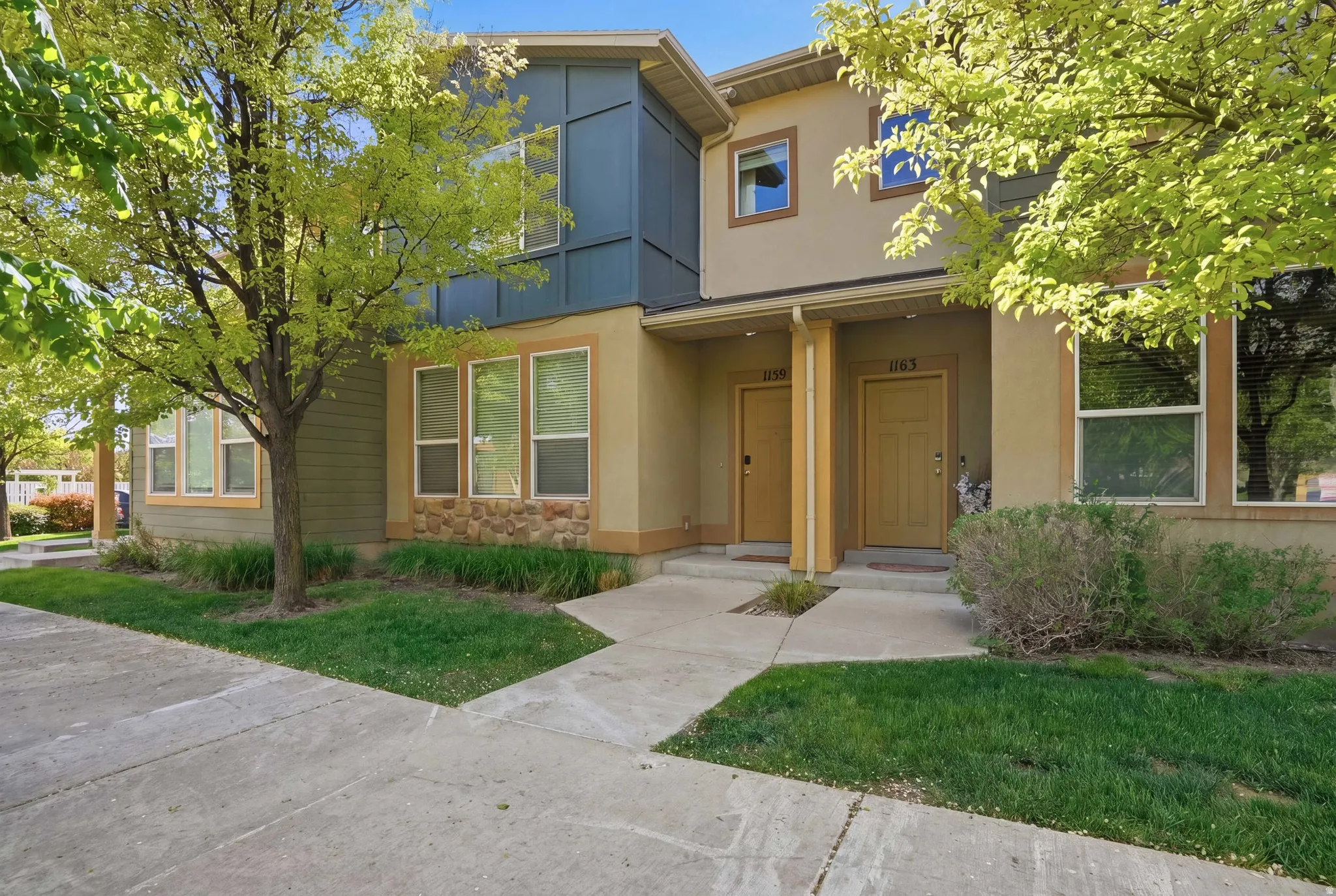 View of front facade with stucco siding, a front yard, and a balcony