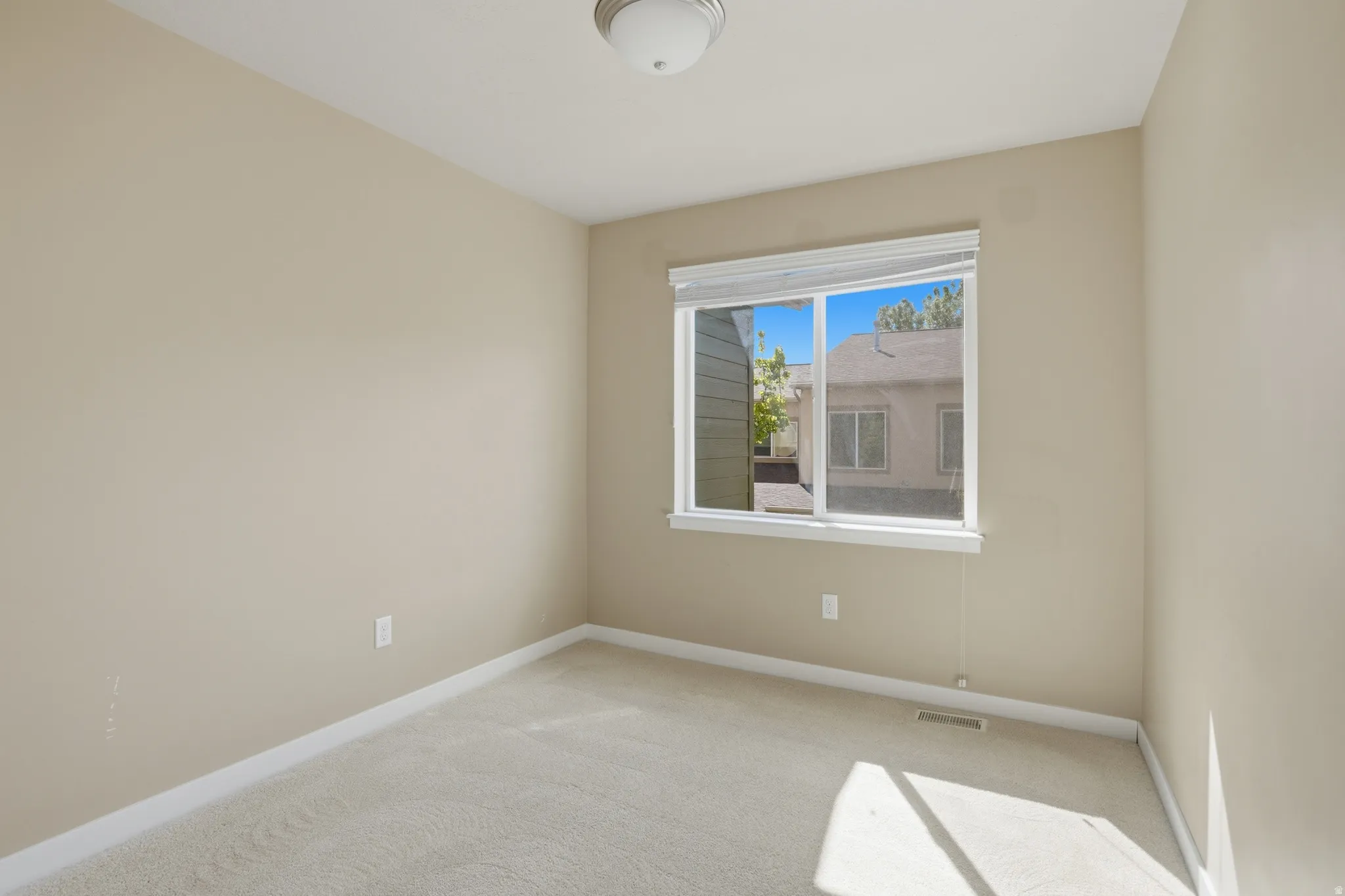 Unfurnished room featuring light carpet and baseboards