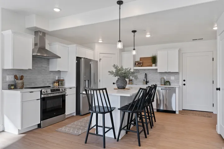 Kitchen featuring stainless steel appliances, white cabinetry, open shelves, and light wood-style floors