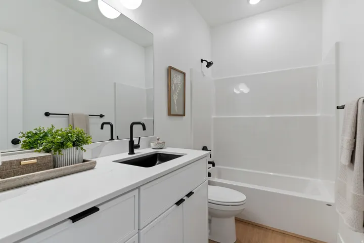 Bathroom with vanity, washtub / shower combination, and light wood-style flooring
