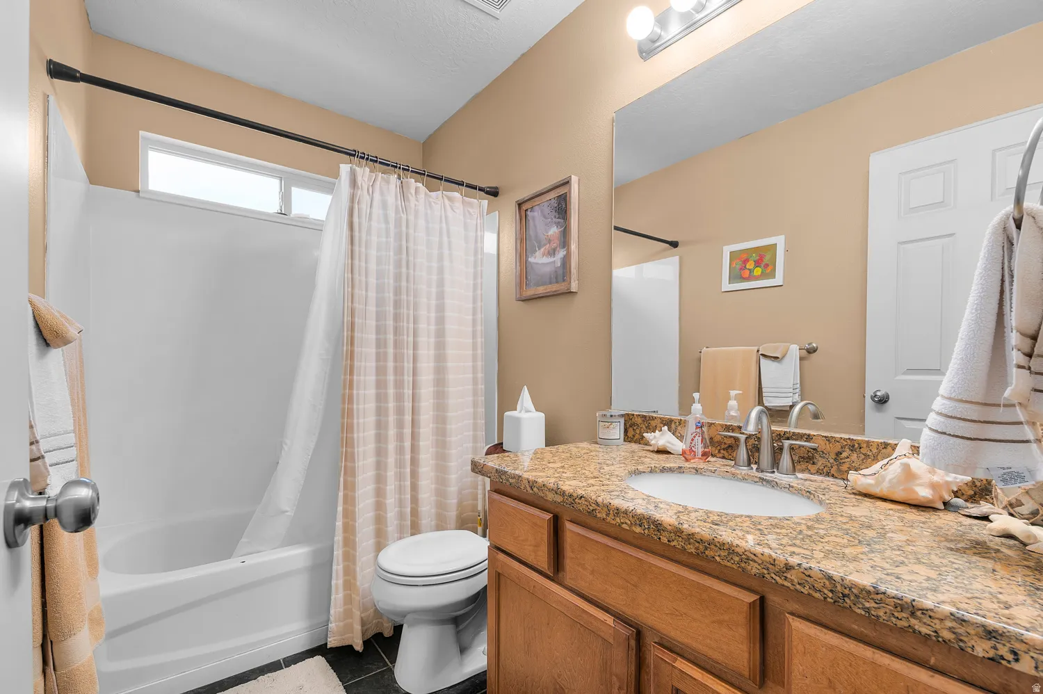 Bathroom with vanity, shower / bath combo with shower curtain, and dark tile patterned floors
