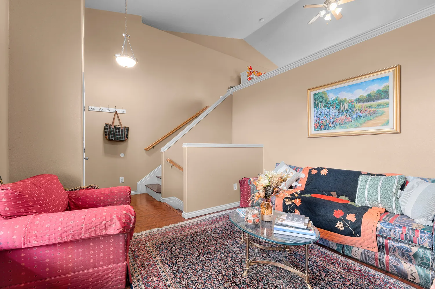 Living room featuring wood finished floors, vaulted ceiling, and a ceiling fan