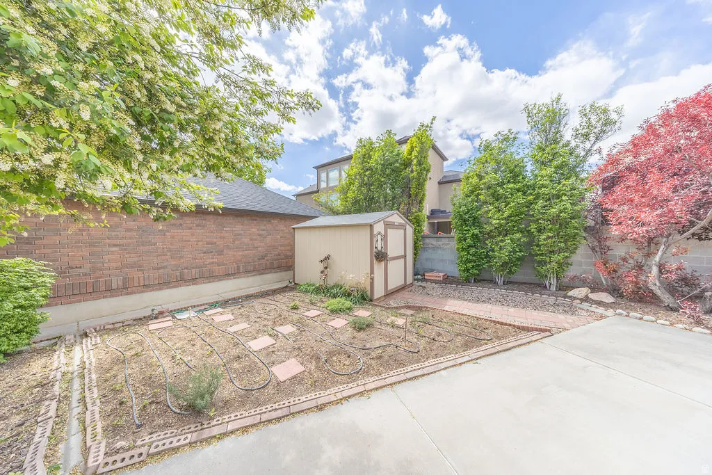 Fenced backyard featuring a vegetable garden and a storage shed