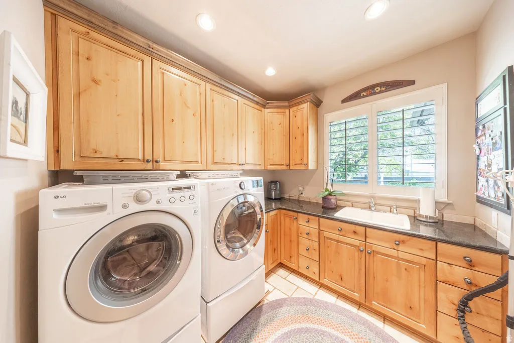 Laundry area featuring separate washer and dryer, light tile patterned flooring, cabinet space, and recessed lighting