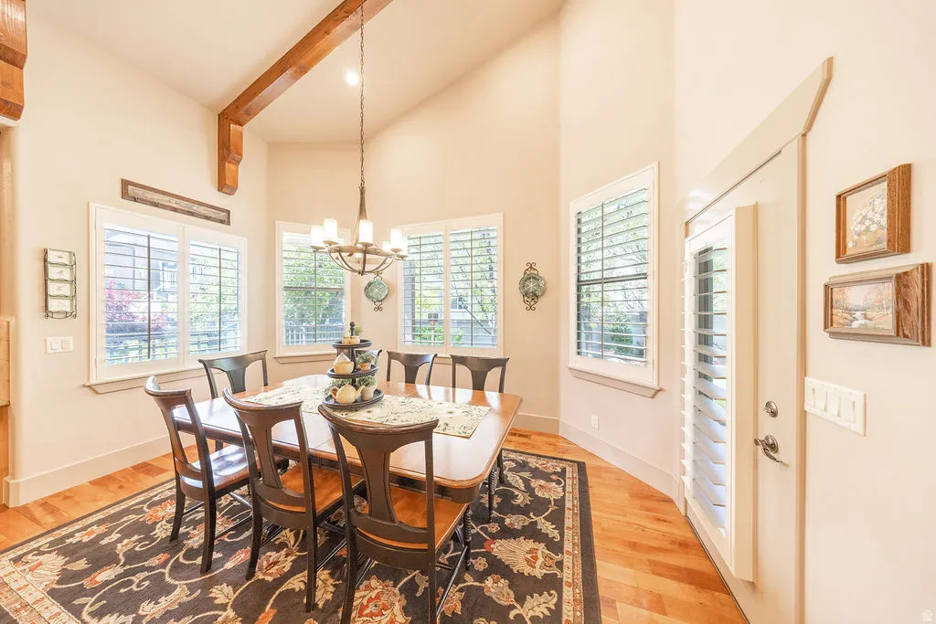 Dining room featuring light wood finished floors, suspended lighting, and a high ceiling