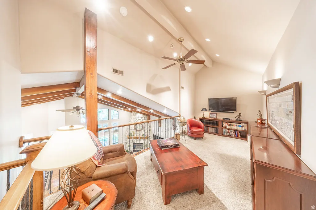 Living room with ceiling fan, a fireplace, and light colored carpet