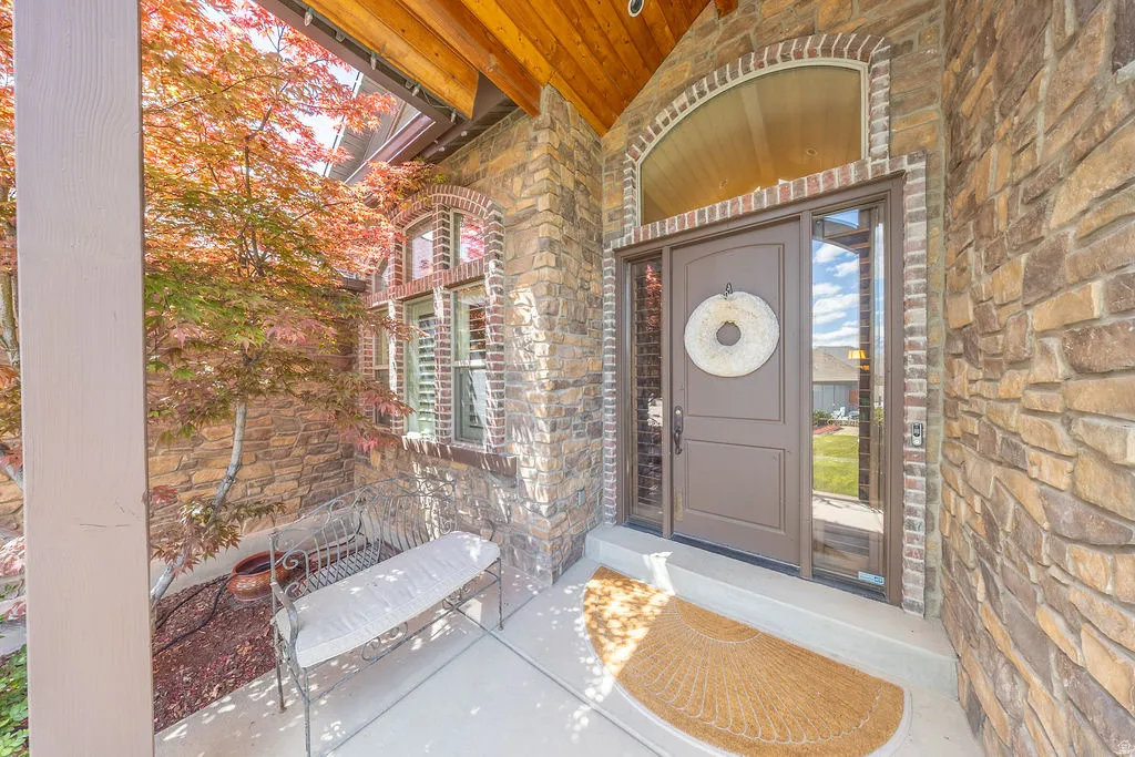 Doorway to property featuring stone siding and covered porch