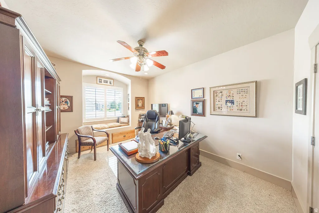 Office area featuring light colored carpet, a ceiling fan, and arched walkways