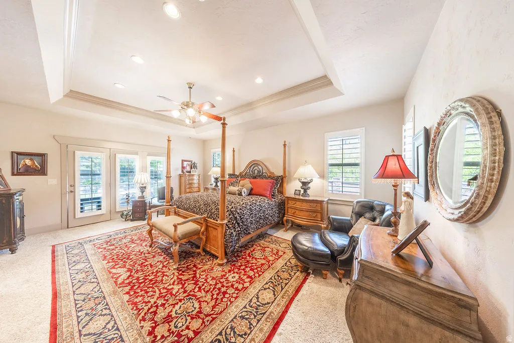 Bedroom featuring access to outside, ceiling fan, a tray ceiling, light colored carpet, and ornamental molding
