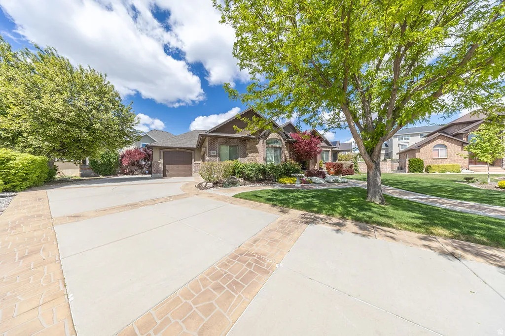 View of front of house featuring concrete driveway, an attached garage, brick siding, and a front yard