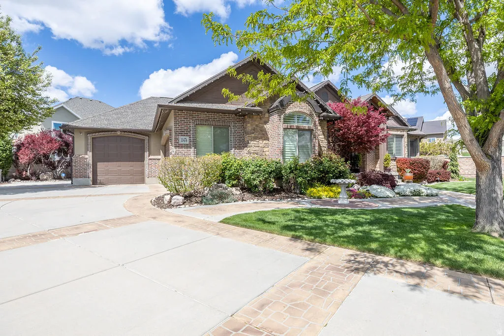 View of front facade with brick siding, a garage, concrete driveway, and a front lawn