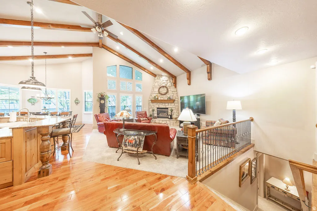Living room featuring light wood-style flooring, a ceiling fan, a fireplace, lofted ceiling, and recessed lighting