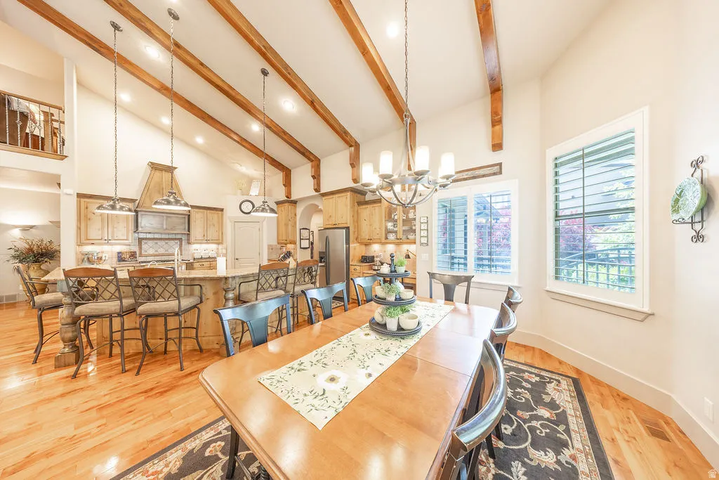 Dining area featuring light wood-style floors, arched walkways, a chandelier, and vaulted ceiling