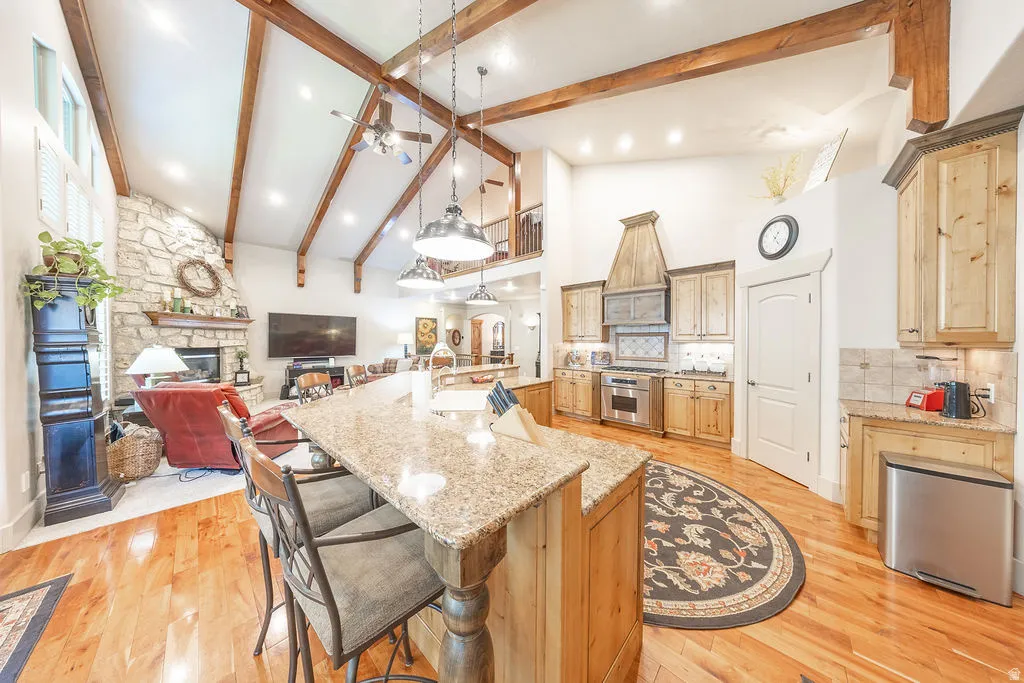 Kitchen with light stone counters, a kitchen breakfast bar, a stone fireplace, open floor plan, and light wood-style floors