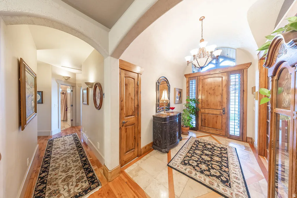 Foyer featuring a chandelier, arched walkways, inlaid floor details, and lofted ceiling