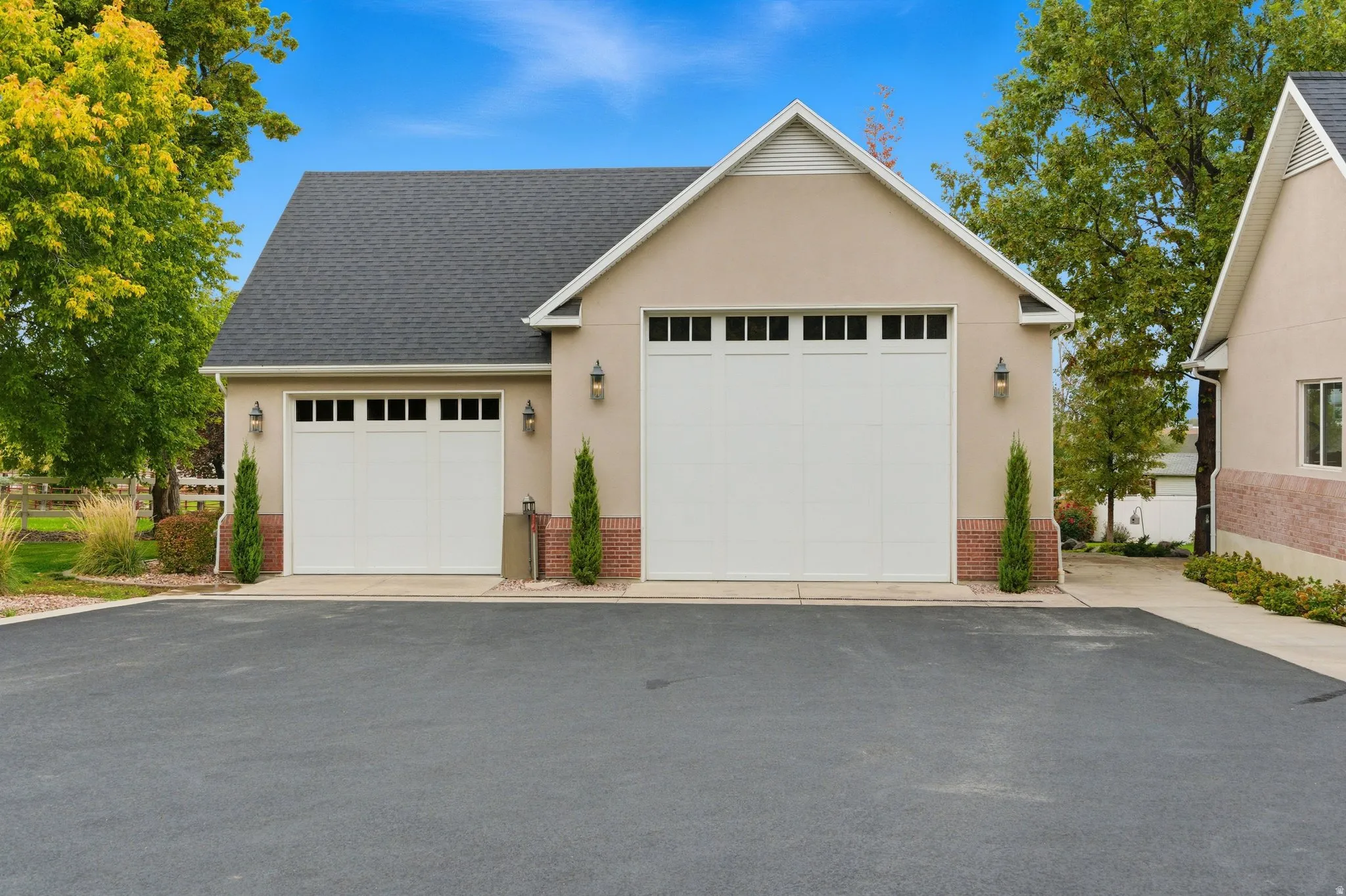 View of front of property featuring brick siding, a shingled roof, a garage, stucco siding, and an outbuilding