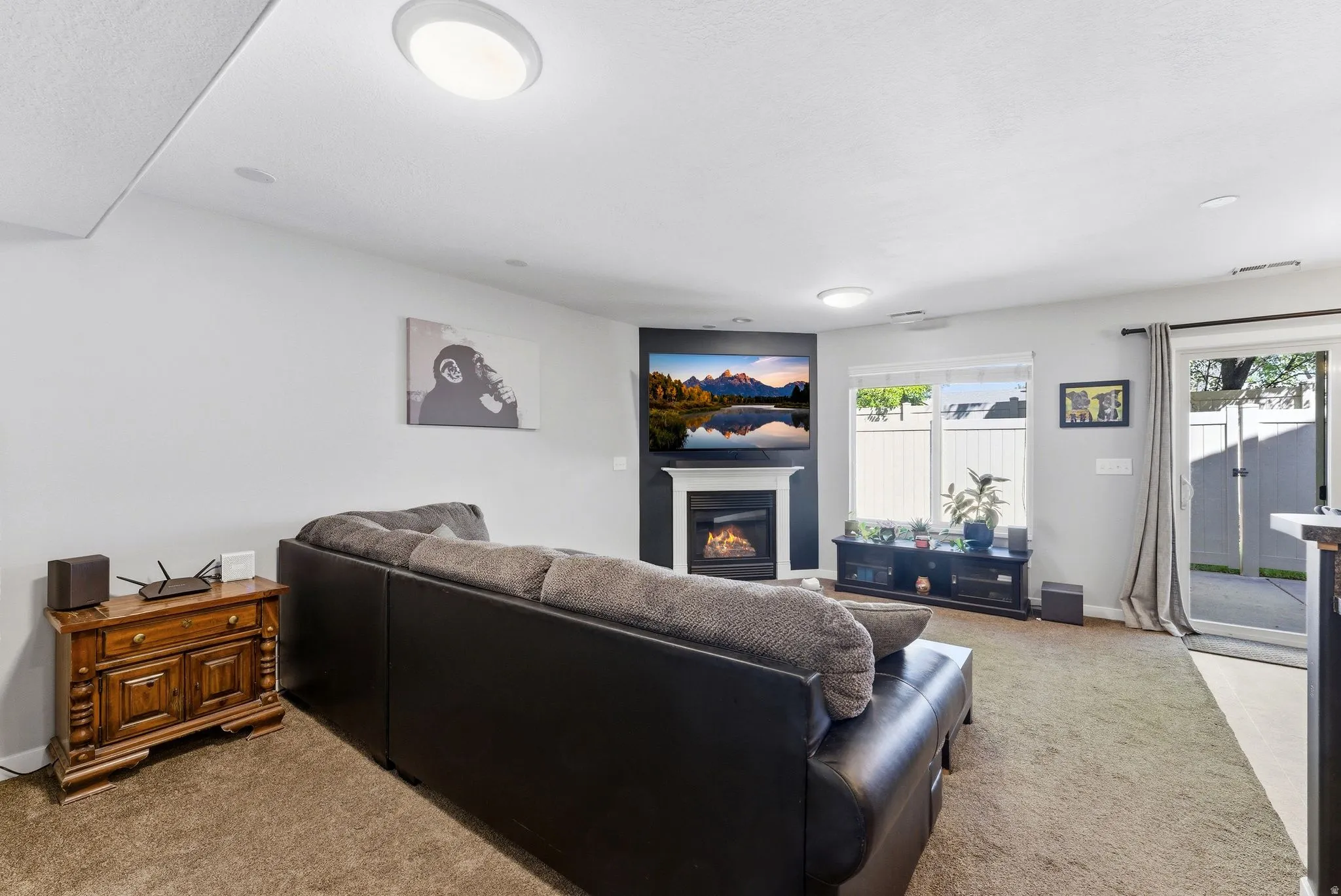 Carpeted living area with baseboards and a glass covered fireplace