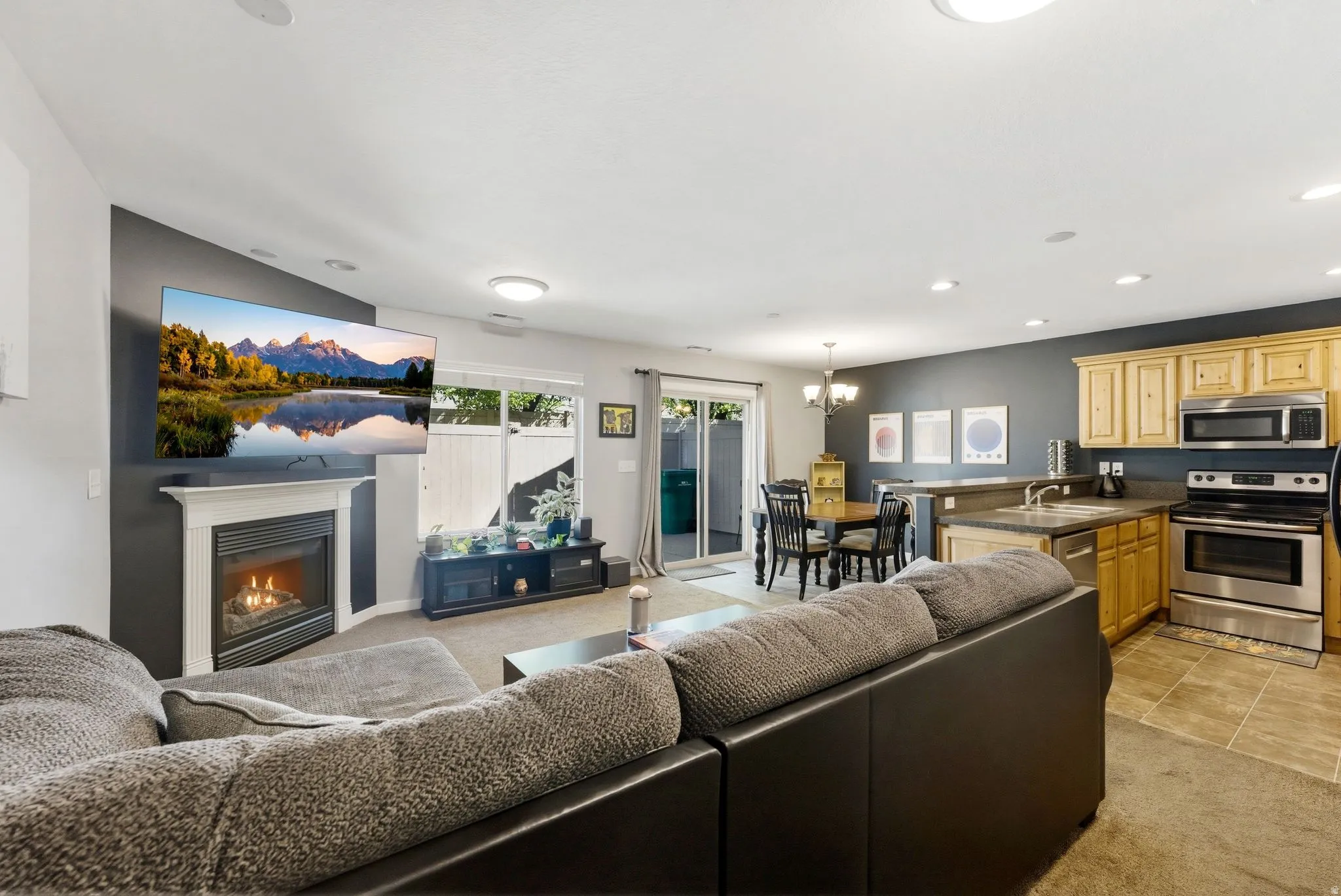Living room featuring a glass covered fireplace, light carpet, and a chandelier