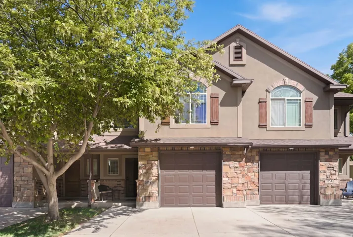 View of front facade featuring a garage and stone siding