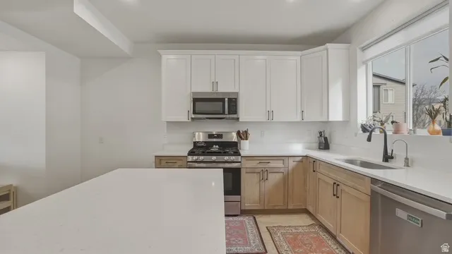 Kitchen with stainless steel appliances, white cabinetry, light stone counters, and recessed lighting