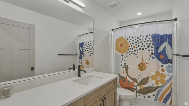 Bathroom with a stall shower, vanity, and recessed lighting