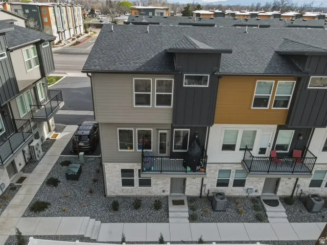 View of front of house with a shingled roof, stone siding, board and batten siding, a residential view, and a balcony