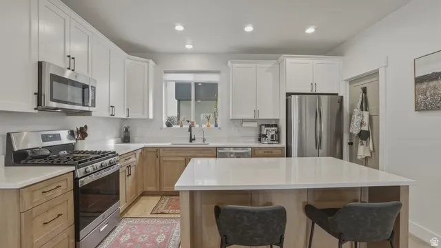 Dual tone kitchen featuring stainless steel appliances, a center island, a kitchen breakfast bar, recessed lighting, and two tone color scheme
