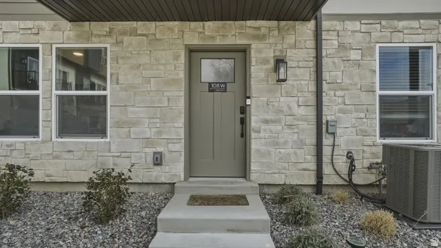 Doorway to property featuring stone siding and covered porch