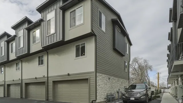 View of side of home with stone siding, an attached garage, and stucco siding