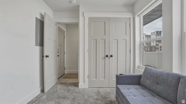 Living area with light carpet and electric panel
