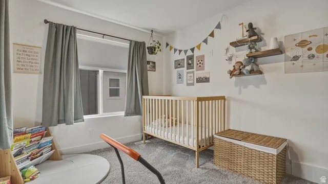 Bedroom featuring a nursery area and carpet flooring