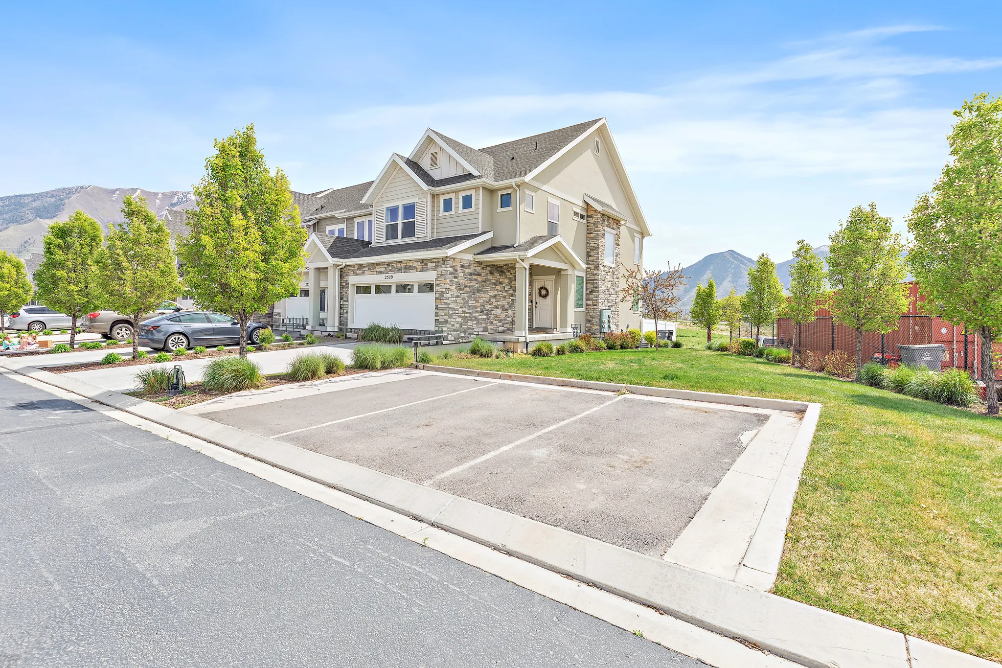 View of front of property featuring stone siding, a mountain view, uncovered parking, and a front yard