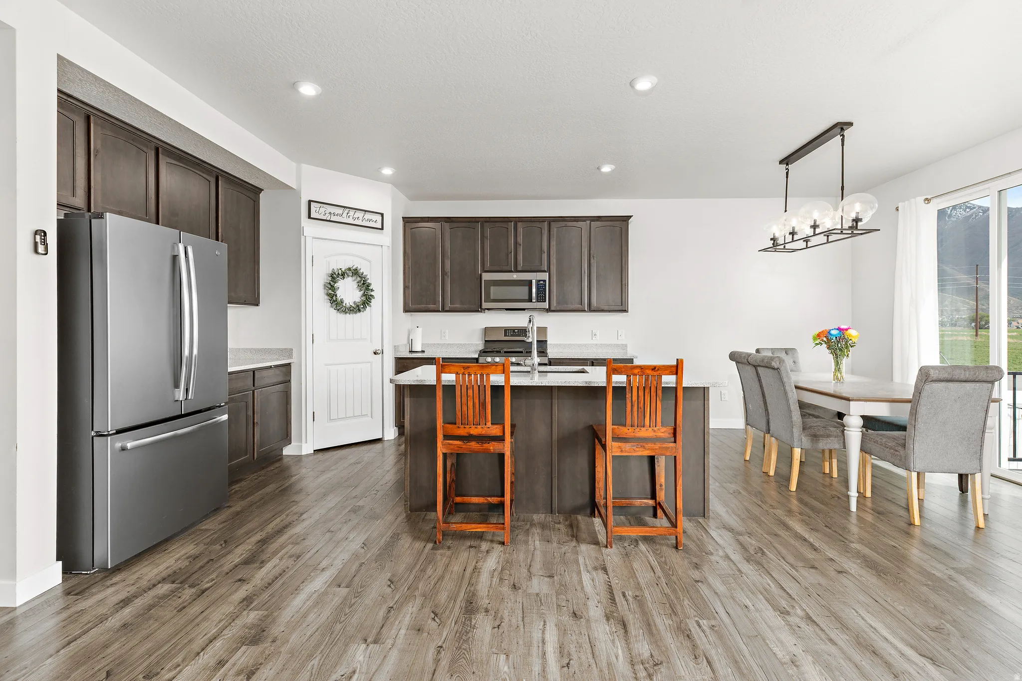 Kitchen featuring stainless steel appliances, dark wood finish cabinetry, light stone countertops, and dark wood-type flooring