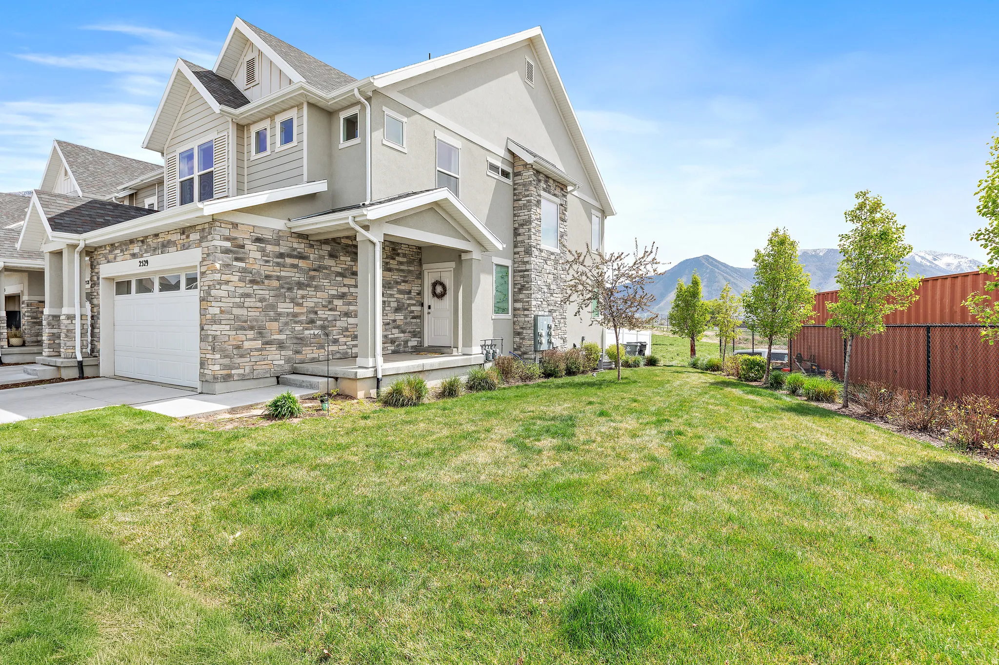 View of front of home featuring stone siding, driveway, a garage, a mountain view, and stucco siding