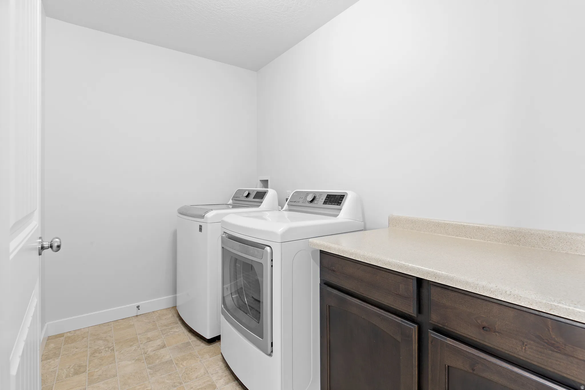 Laundry room featuring washer and dryer, a textured ceiling, and stone finish flooring