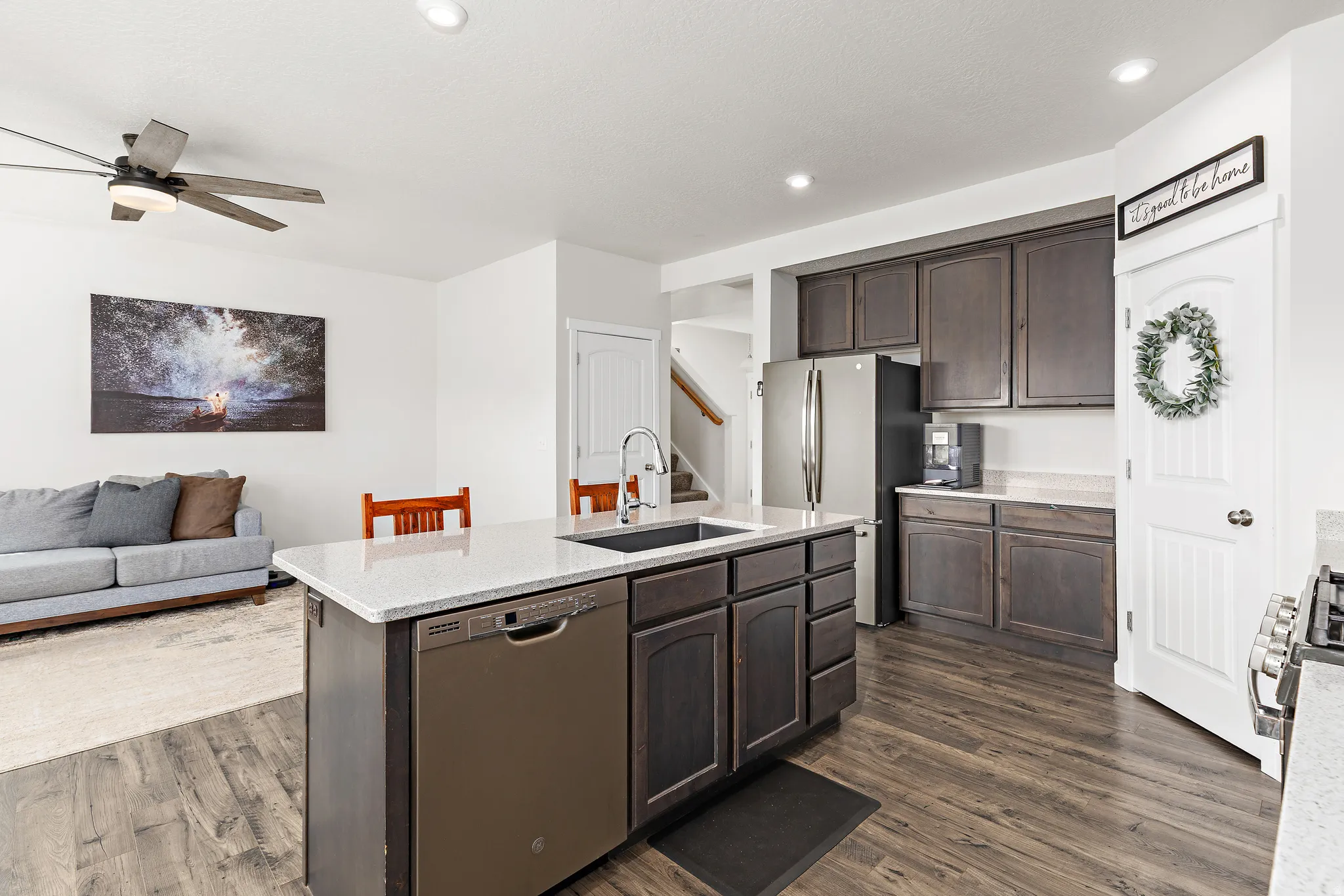 Kitchen with dark wood finish cabinetry, stainless steel appliances, open floor plan, dark wood-style floors, and recessed lighting