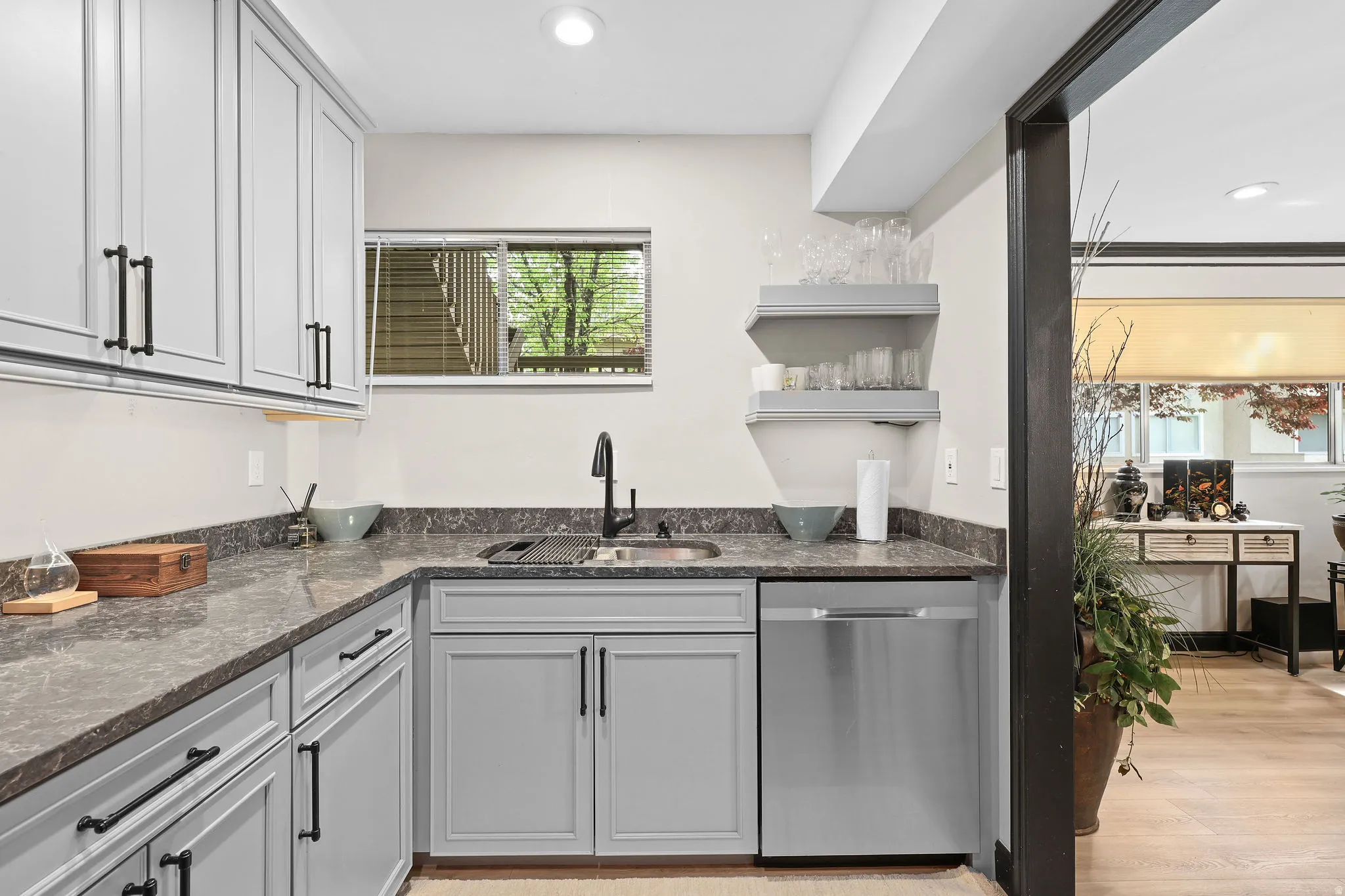 Kitchen featuring dishwasher, dark stone counters, open shelves, recessed lighting, and light wood-type flooring