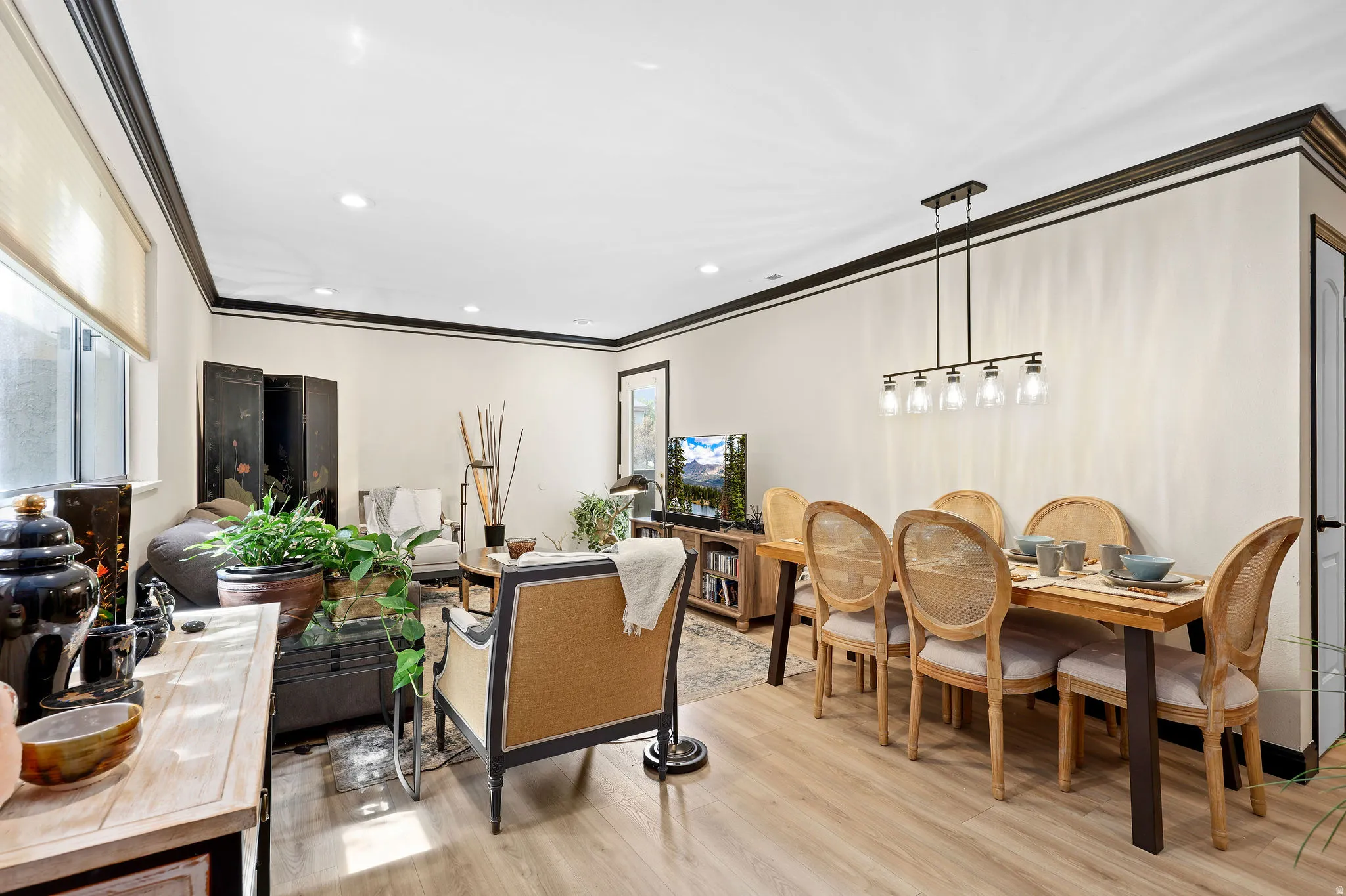 Dining space with light wood-style flooring, crown molding, and recessed lighting