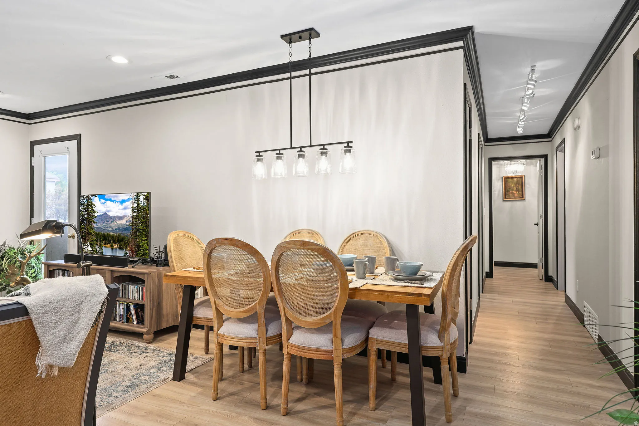 Dining space featuring crown molding, light wood-type flooring, and rail lighting