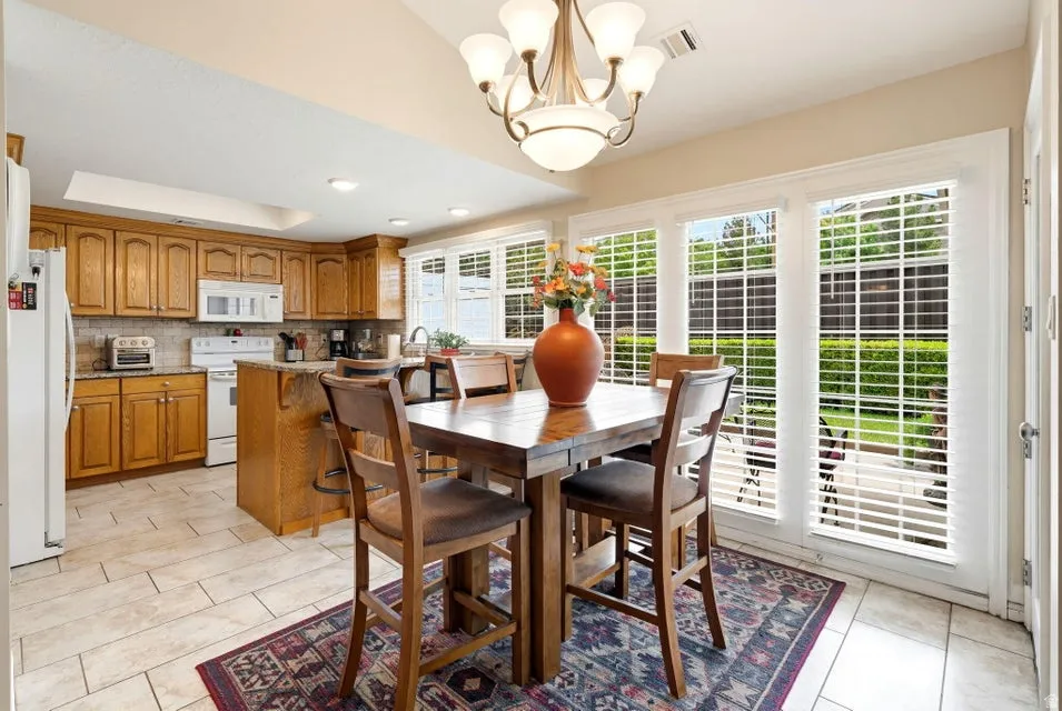 Dining area with hanging lights, light tile patterned floors, and a raised ceiling