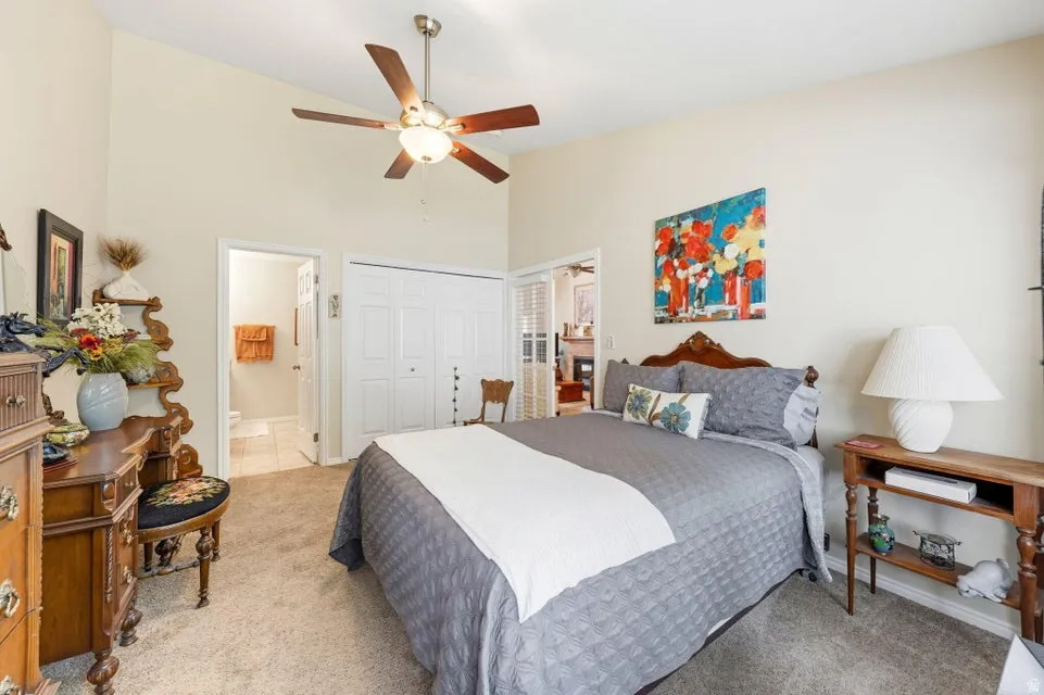 Bedroom featuring ensuite bath, a closet, vaulted ceiling, and carpet