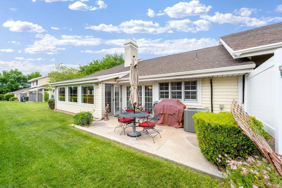 Back of property featuring a lawn, a patio area, a shingled roof, and a chimney