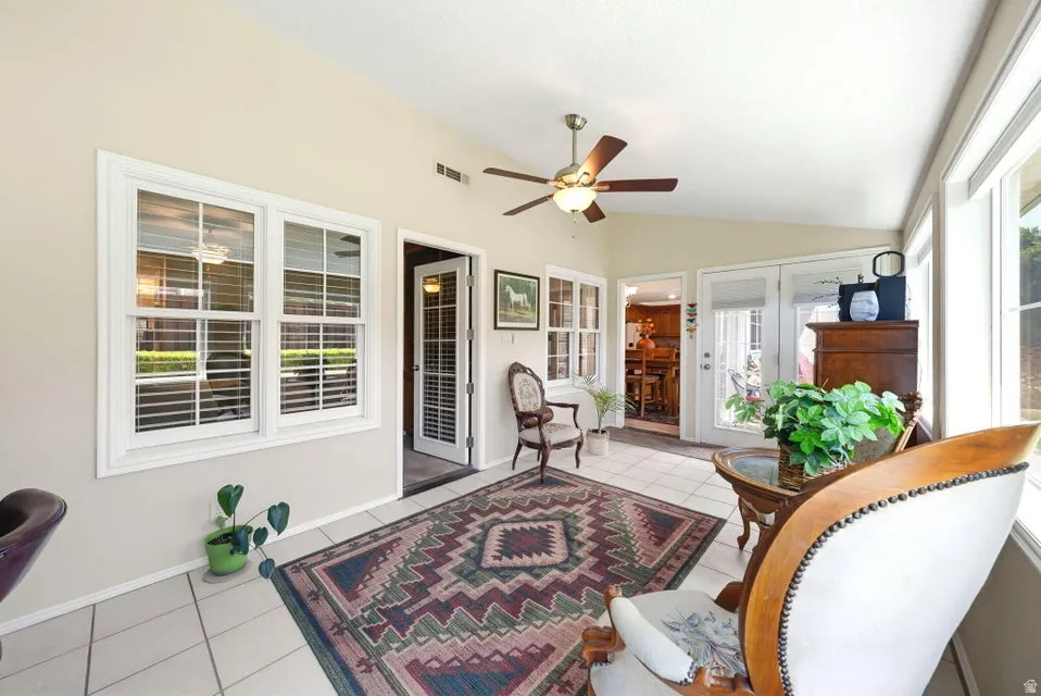 Sunroom / solarium featuring french doors, a ceiling fan, and lofted ceiling