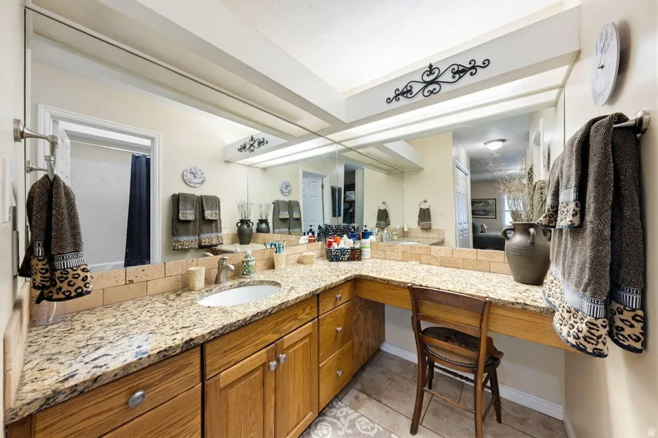 Full bath featuring vanity, curtained shower, light tile patterned flooring, and ensuite bathroom