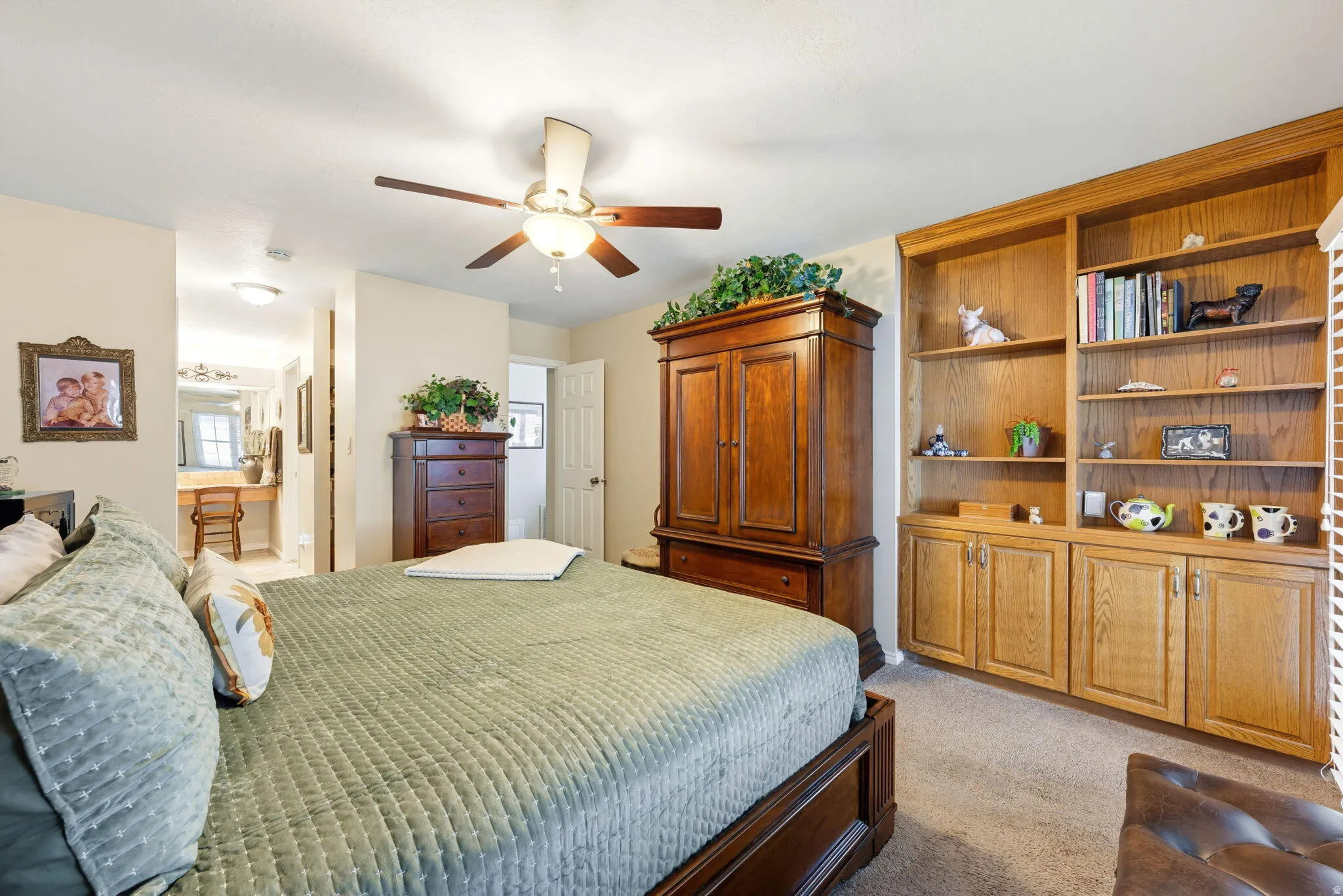 Bedroom featuring light carpet, a ceiling fan, and ensuite bath