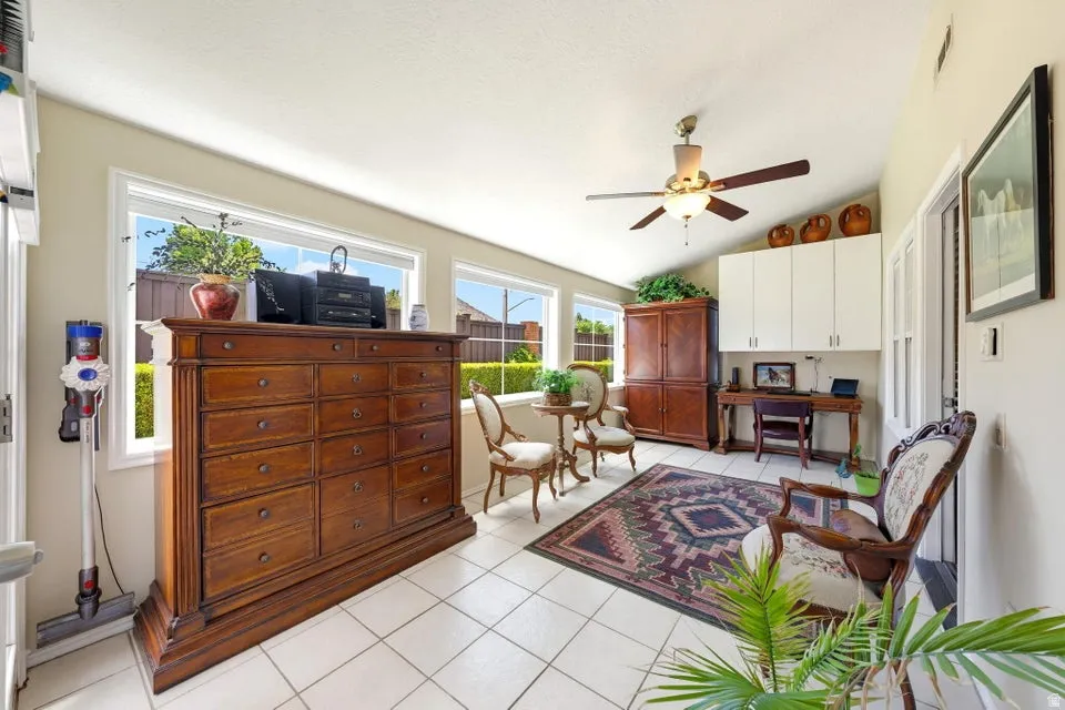 Living area with light tile patterned floors, a ceiling fan, and vaulted ceiling