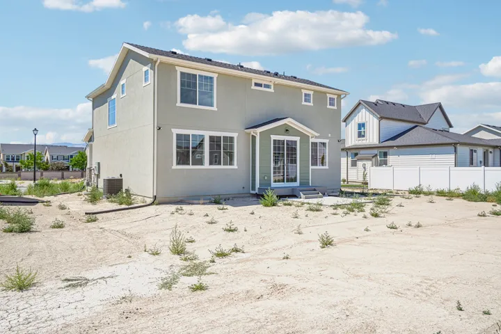 Two-story residence featuring light stucco siding, multiple windows with white trim, and a sliding glass door providing exterior access