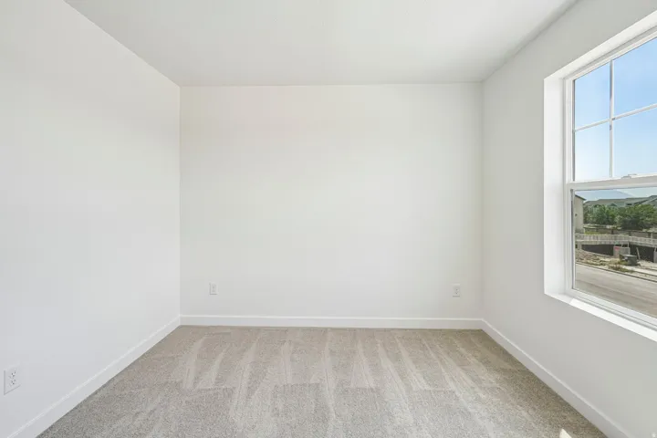 Bright room with a large window, neutral carpet, and white walls