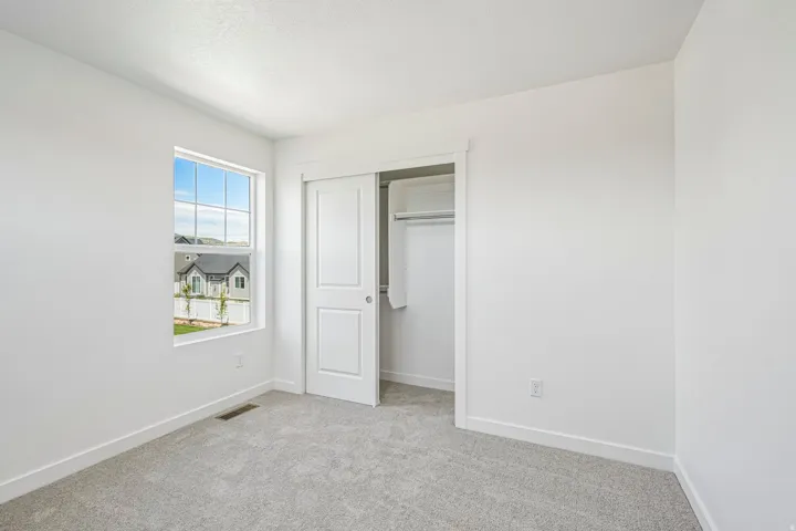 Bright room featuring light gray carpeting, white walls, and a window with grid panes